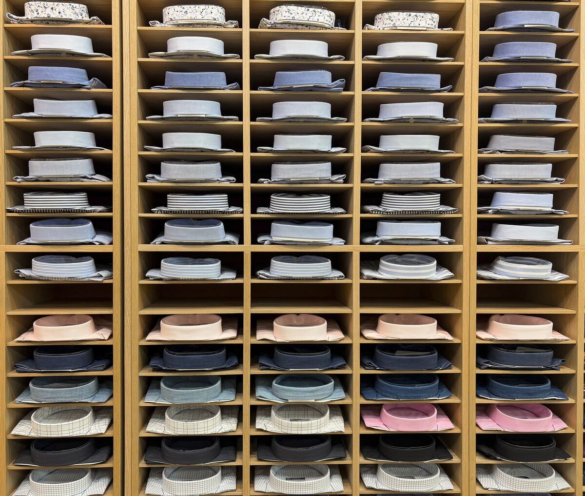 Pared de estantes de madera con camisas dobladas y ordenadas